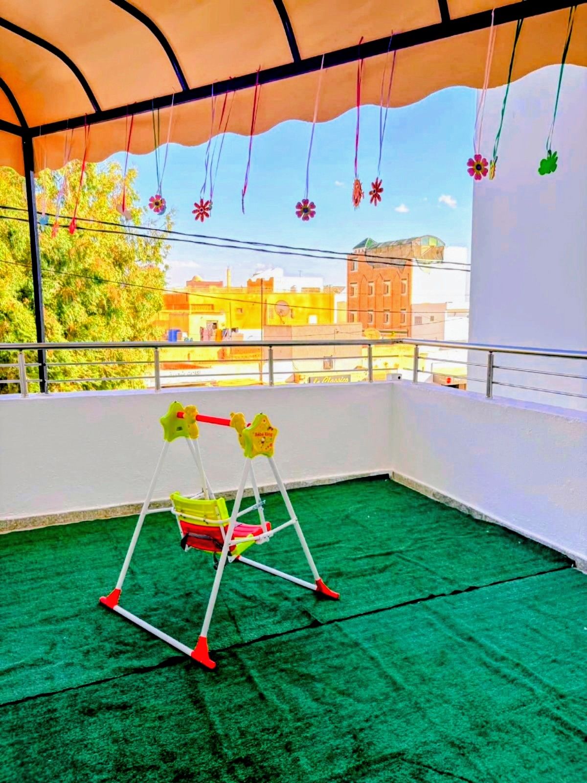 Balcon aménagé pour les enfants : gazon, balançoire et fleurs suspendues