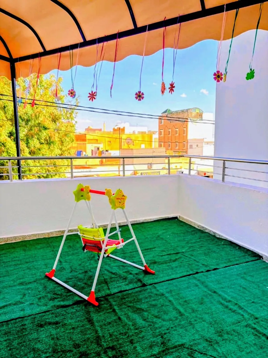 Balcon aménagé pour les enfants : gazon, balançoire et fleurs suspendues