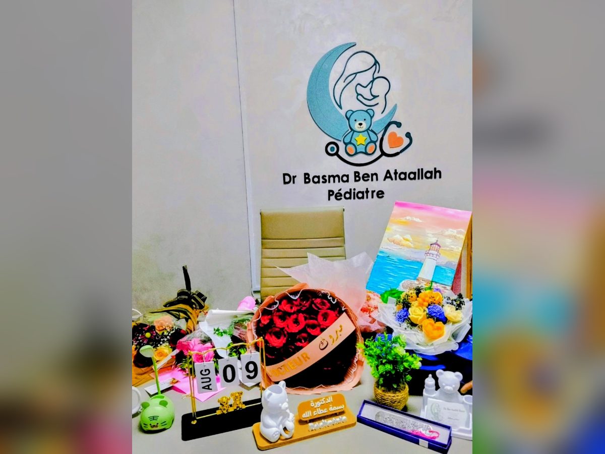 Bureau de Dr Basma avec le logo du cabinet au mur, fleurs et cadeaux d'ouverture