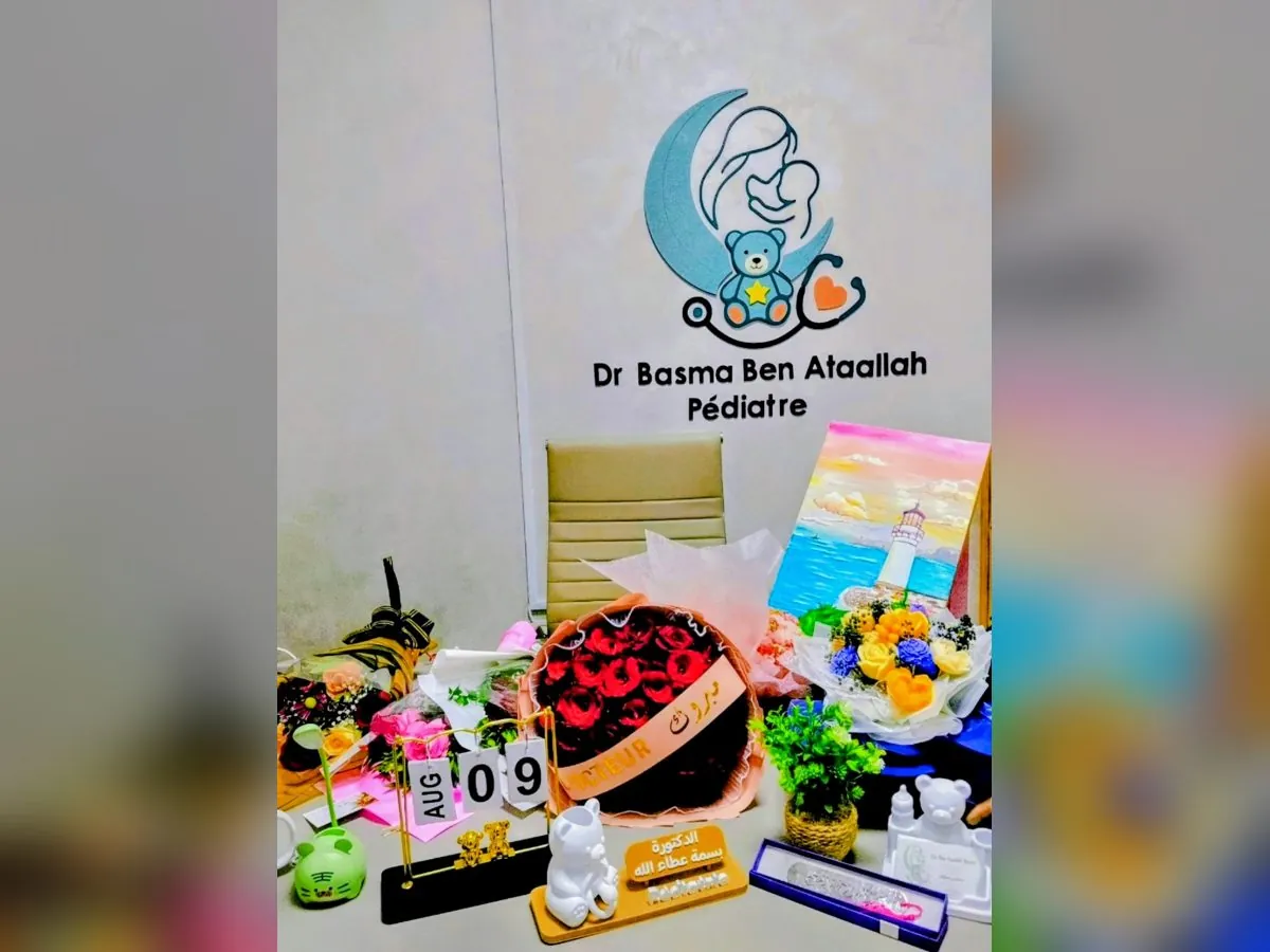 Bureau de Dr Basma avec le logo du cabinet au mur, fleurs et cadeaux d'ouverture