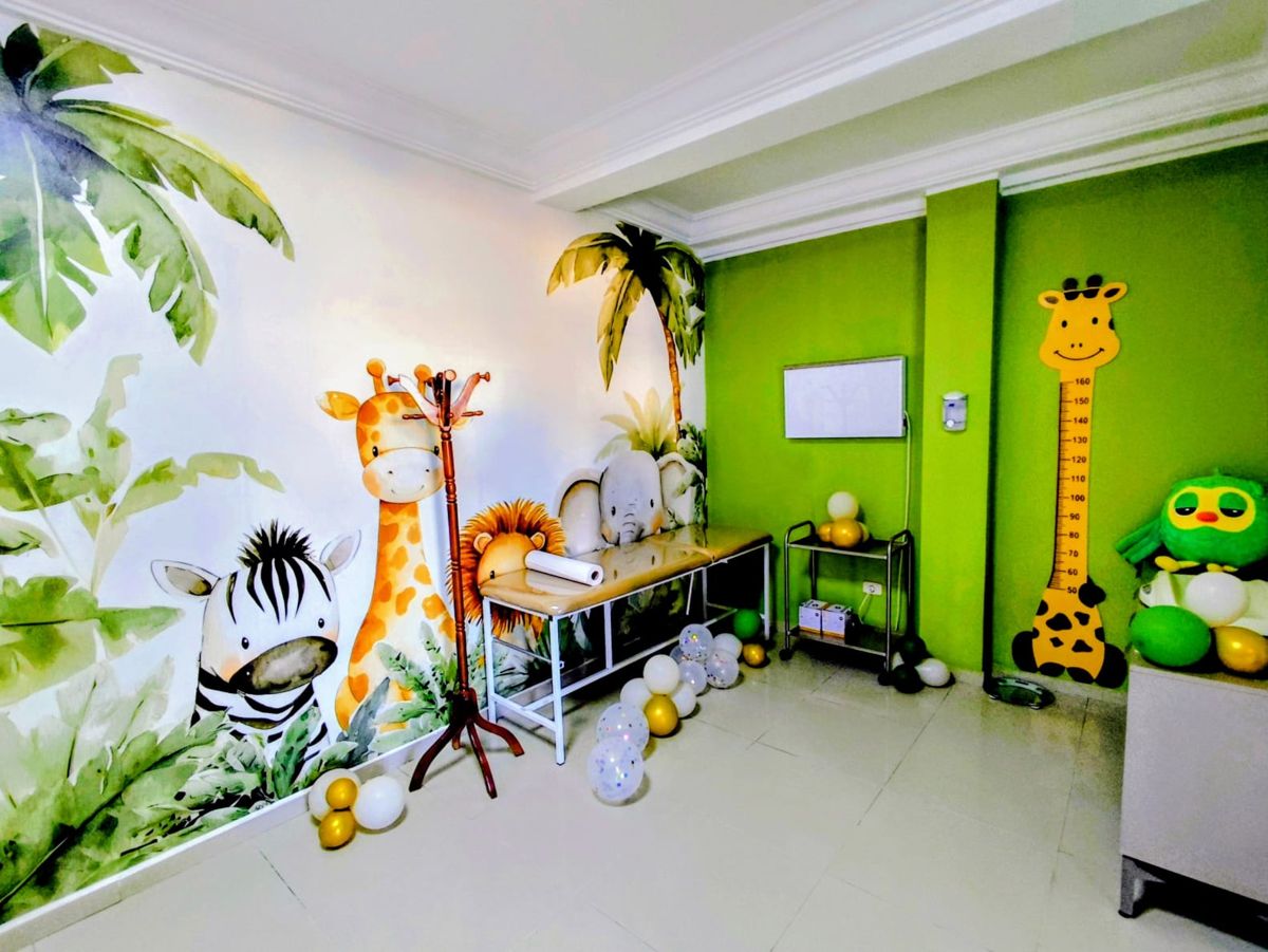 Salle de consultation décorée sur le thème de la savane : fresque zèbre, girafe, lion et éléphant, table d'examen et toise girafe